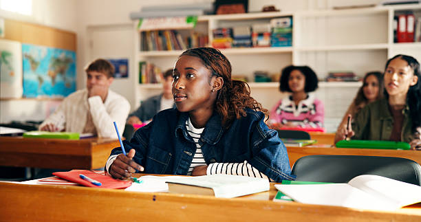 istock Lesson, girl student and attention in classroom for learning, academic information and education. Teenager, people and listening with books at high school for development, writing notes and knowledge 2241360538