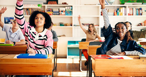 istock Question, class and students in classroom at high school with learning, education or participation in lesson. Teen, group and people raising hands for knowledge, academic development and interaction 2241360540