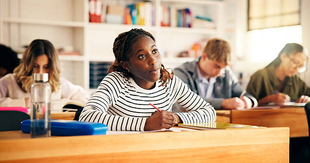 istock Learning, classroom and girl writing notes in high school for test, education or academic knowledge. Teen students, lesson or study in academy for assessment, scholarship exam or quiz for development 2241360600