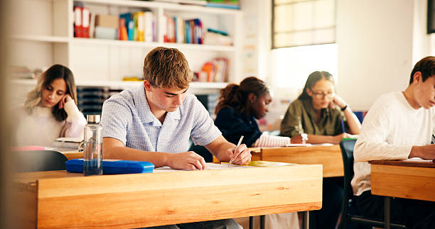 istock High school students, boy and writing in lesson for assessment, essay assignment or learning. Teenager, education and people with aptitude test in classroom for scholarship and curriculum knowledge 2241360609