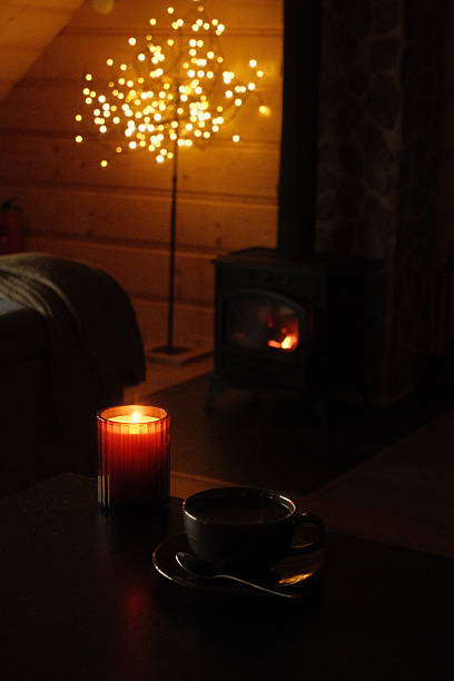 istock Cozy interior scene with warm candlelight, coffee cup, and glowing decorative tree lights 2241362356
