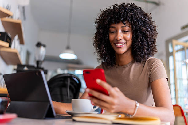 istock Young woman smiling using smartphone in a cafe 2241362469