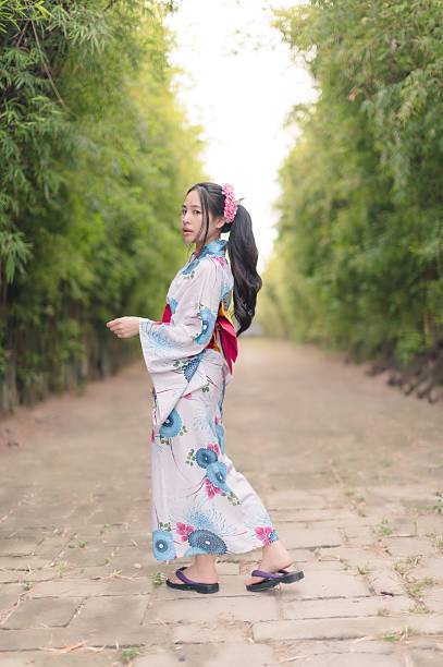 istock Young Woman in Kimono Walking Through Peaceful Bamboo Pathway 2241364811