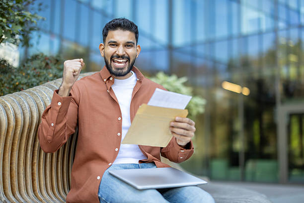 istock Excited man holding document and celebrating success outdoors 2241365314