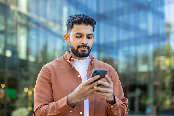 istock Young businessman using smartphone in front of modern office building 2241365393