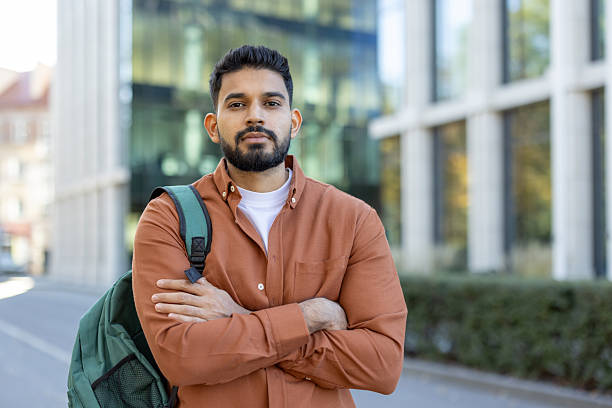 istock Portrait of a young man with a beard, standing confidently outdoors with a backpack. 2241365394