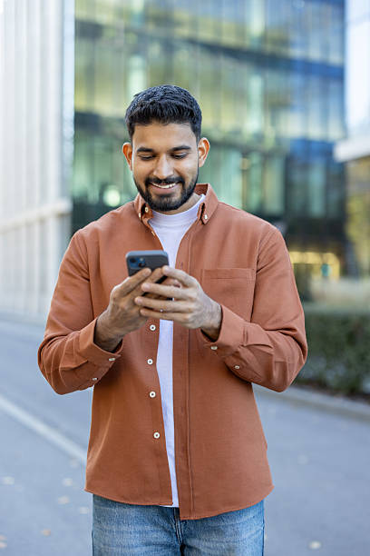 istock Young man happily using his smartphone in a modern urban setting 2241365396