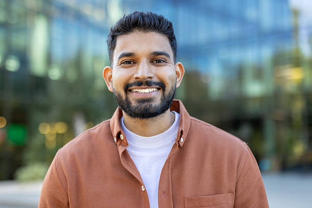 istock Smiling man outdoors near modern glass building on a sunny day 2241365403