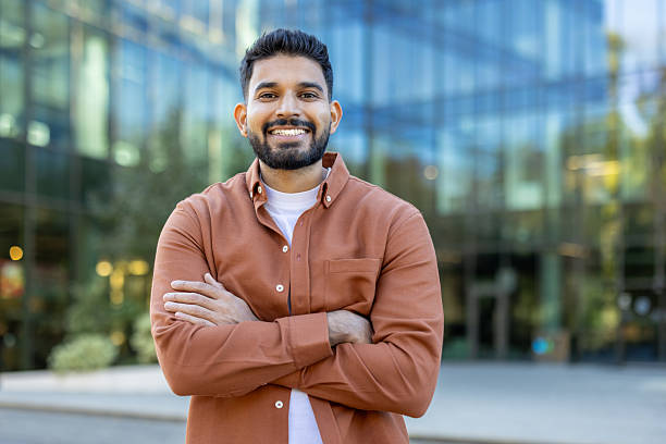 istock A smiling, handsome man poses confidently with crossed arms outside a modern building. 2241365411