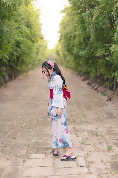 istock Young Woman in Kimono Walking Through Serene Bamboo Pathway 2241365833