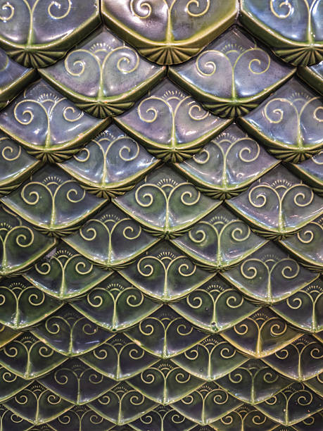 istock Close-up of ornate glazed ceramic tiles arranged in an overlapping scale pattern, featuring intricate traditional motifs in varying shades of dark teal and purple. A rich, textured background. 2241366197