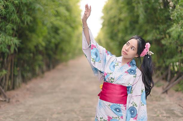 A young woman in a traditional kimono poses gracefully in a bamboo pathway, expressing joy and serenity amidst nature's beauty. A perfect cultural moment.