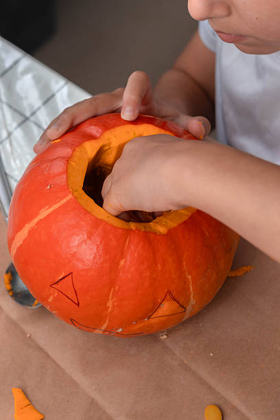 istock A child is scooping out the flesh from a pumpkin, preparing it for carving. 2241370092