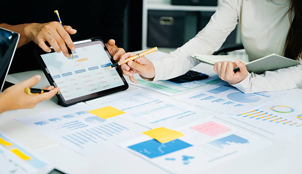 istock Business documents on office table with smart phone and calculator digital tablet and graph business with social network diagram and two colleagues discussing data working in the office 2241371516