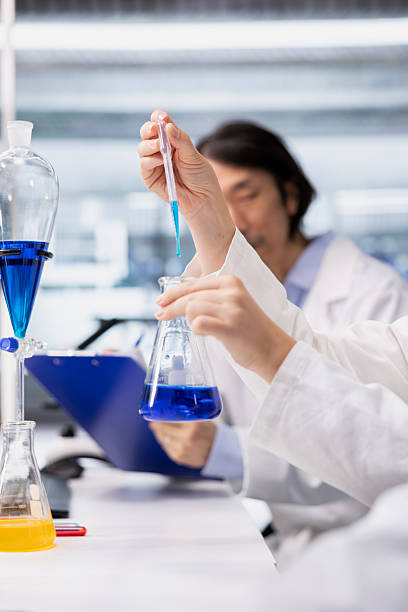 istock Close up of microbiologists brainstorming, using pipette to dispense reagent 2241373655
