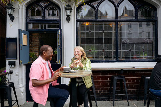 istock Cheerful senior couple sitting at table and drinking coffee outside pub 2241374714