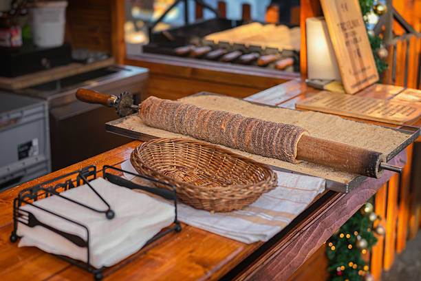 Trdelnik, also known as chimney cake, is freshly baked and covered in sugar at festive Christmas market stand. Concept of Trdelnik, sweet tradition, authentic holiday street food