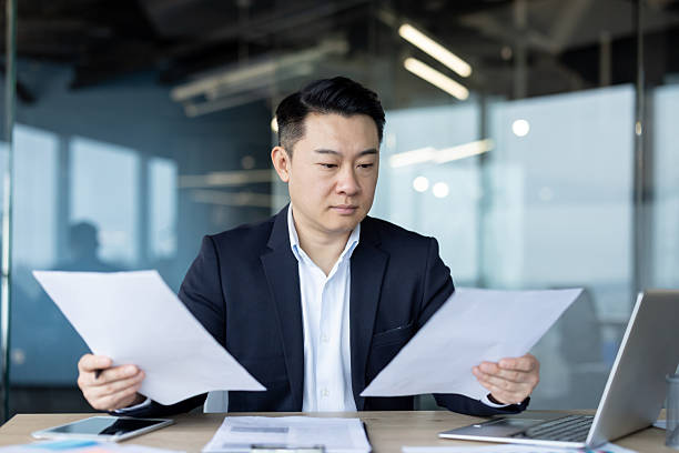 istock Asian young man in a suit sitting in the office at his workplace and working with documents and a project 2241375611