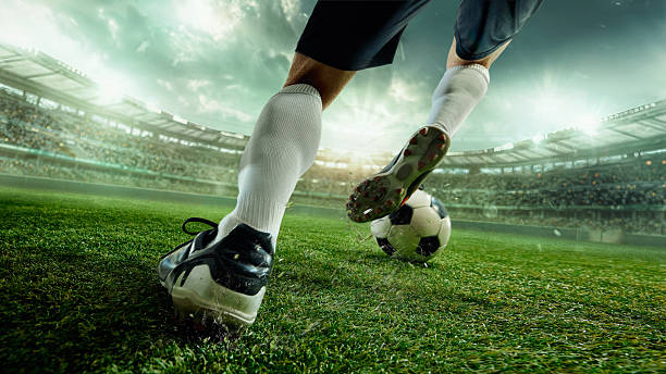 Faceless soccer player in white socks striking ball with power on green 3D stadium field stock photo
