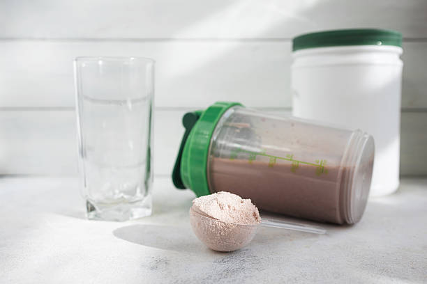 istock Chocolate whey protein powder, shaker with drink, white plastic protein jar and empty glass on light surface, fitness nutrition and supplement concept 2241376611