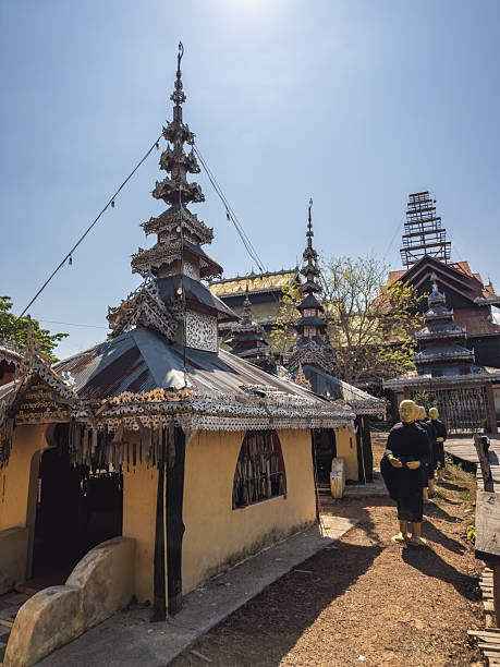 istock A traditional Kayan Buddhist monastery in Myanmar, featuring unique multi-tiered spires, intricately decorated eaves, and a row of serene monk statues under a clear sunny sky. Reflects rich cultural 2241377406