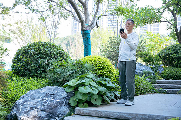 An old Asian man using a mobile phone in the park
