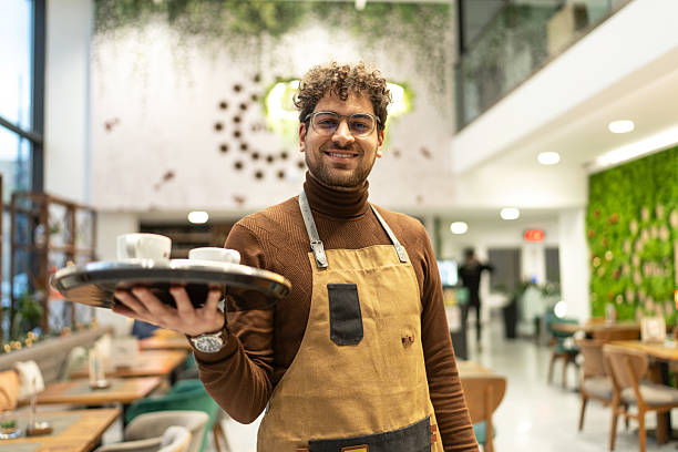 istock Waiter smiling offering coffee in a modern restaurant interior 2241378757
