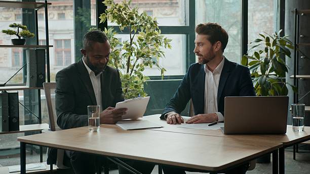istock Two happy diverse business men team contract signing papers documents teamwork cooperation multiracial businessmen Caucasian man and African American coworkers conclude agreement partnership in office 2241380383