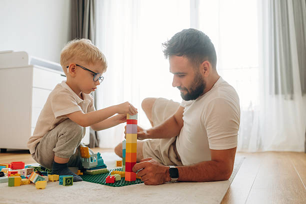 istock Parenting conception. Father is playing in the room with his little son with construction sets 2241384496