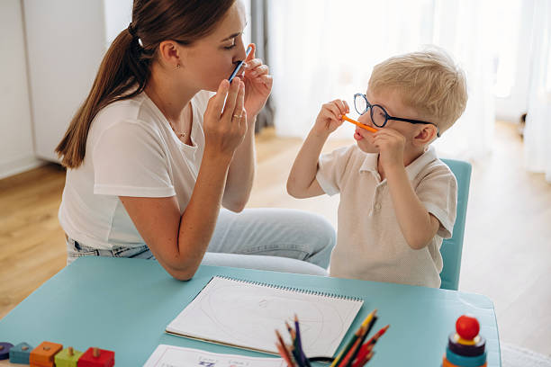 istock Having fun fun pencils. Speech therapist is with young boy indoors 2241385120