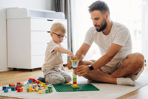 istock Parenting conception. Father is playing in the room with his little son with construction sets 2241385122