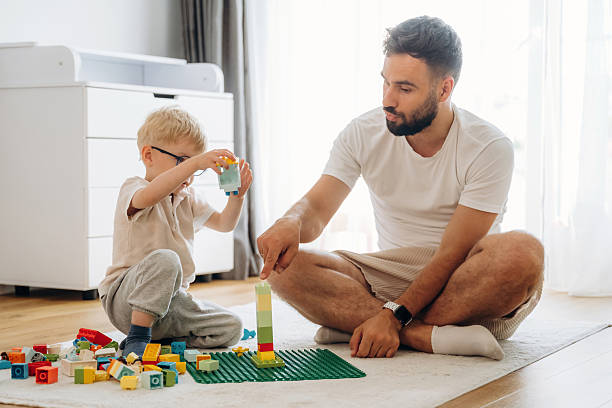 istock Parenting conception. Father is playing in the room with his little son with construction sets 2241385138
