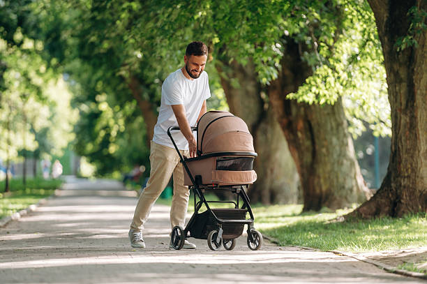istock Happy parent. Father is with cradle, having a walk in the park 2241387253