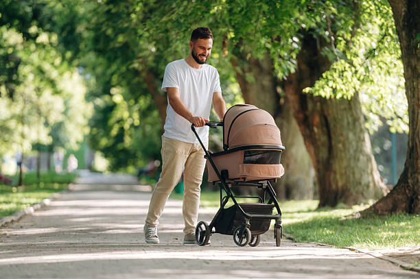 istock Happy parent. Father is with cradle, having a walk in the park 2241387254