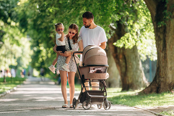 istock Front view, smiling. Couple is with daughter and cradle are having a walk 2241387301