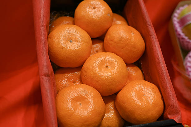 Many fresh mandarins in a wooden stand on a table