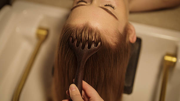 istock Hands massage head with comb. Woman relaxes in head spa. 2241387658