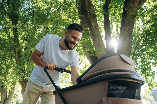 istock Very happy, parenting conception. Father is with cradle, having a walk in the park 2241388124