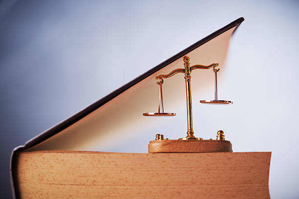Legal Law concept - Open law book with a libra scale on table .