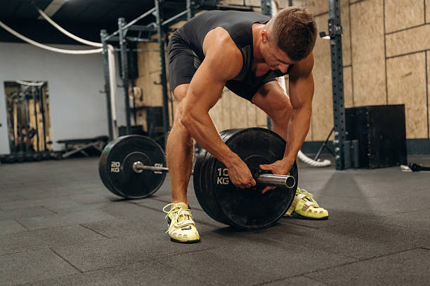 istock Adding more weight. Athletic man performing weightlifting exercises with a barbell in a gym 2241390472