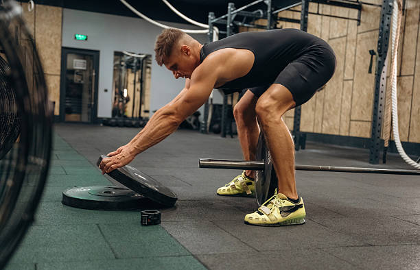 istock Adding more weight. Athletic man performing weightlifting exercises with a barbell in a gym 2241390475