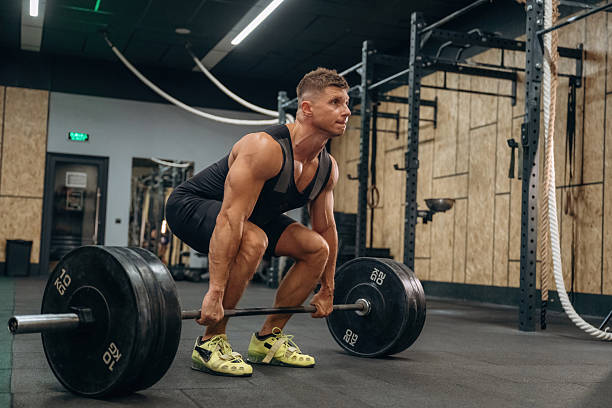istock Ready for lifting. Athletic man performing weightlifting exercises with a barbell in a gym 2241390498