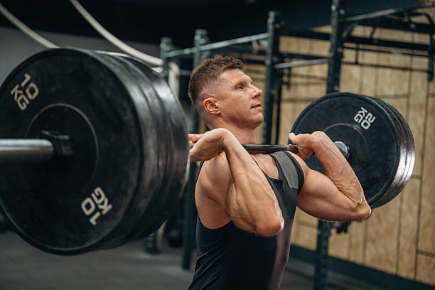istock Conception of weightlifting. Athletic man is doing exercise with a barbell in a gym 2241390501