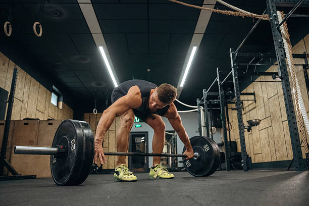 istock Conception of weightlifting. Athletic man is doing exercise with a barbell in a gym 2241390516
