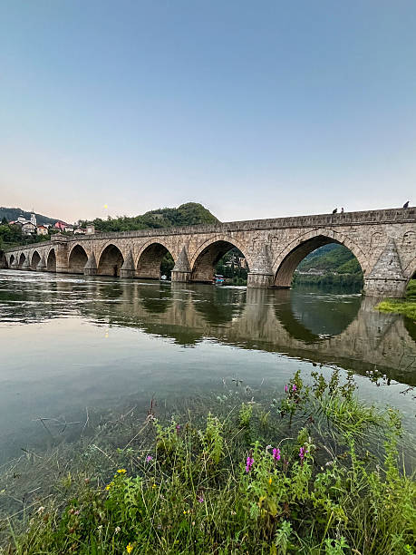 istock Historic stone bridge with illuminated arches over the Drina River at dusk. 2241390718