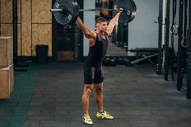 istock Side view. Athletic man performing weightlifting exercises with a barbell in a gym 2241391324