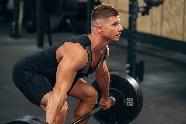 istock Side view. Athletic man performing weightlifting exercises with a barbell in a gym 2241391328