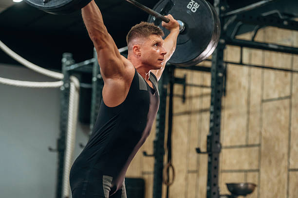 istock Side view. Athletic man performing weightlifting exercises with a barbell in a gym 2241391347