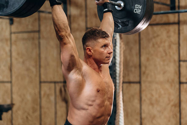 istock Focused on right technique. Athletic man performing weightlifting exercises with a barbell in a gym 2241391453