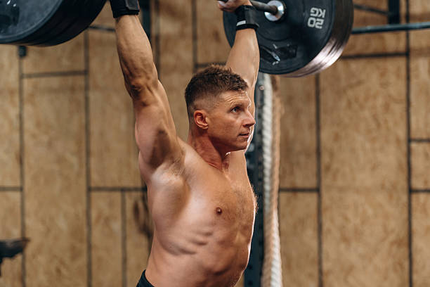 istock Focused on right technique. Athletic man performing weightlifting exercises with a barbell in a gym 2241391454